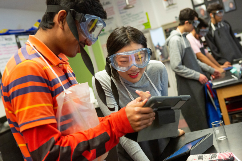 A high school boy and girl work on a chemistry experiment during class.