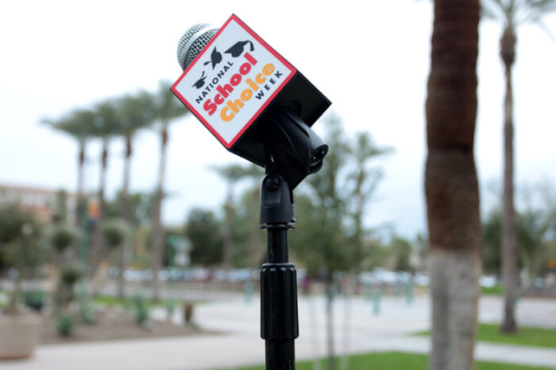 A microphone showing "National School Choice Week" stands on a school campus.