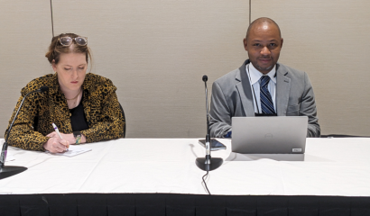 A man and a woman sit at a table next to each other.