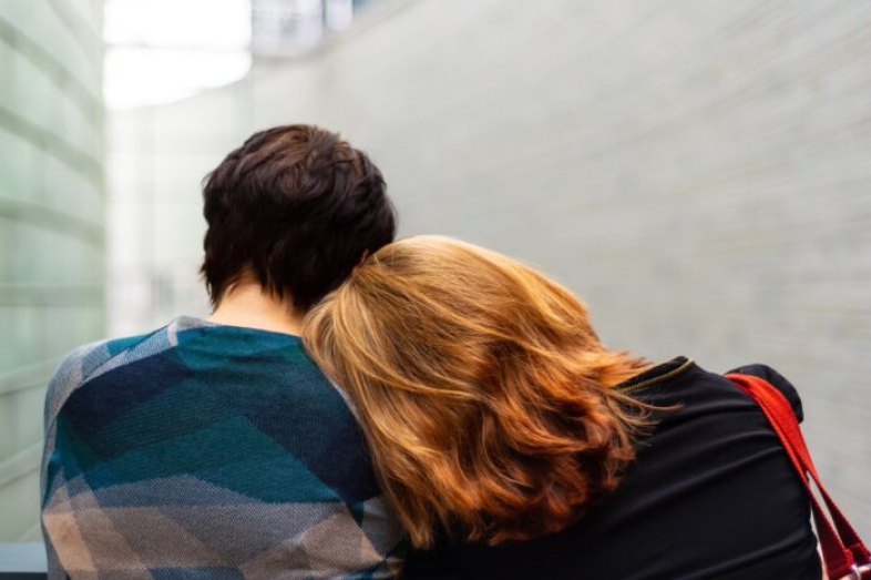 A woman lays her head on another's shoulder.